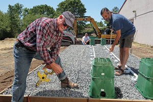 Mike Treinen on a job site, checking a level on a gravel pad