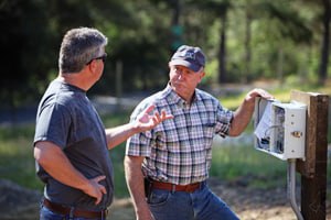 Mike Treinen discussing a property with a client in a wooded setting